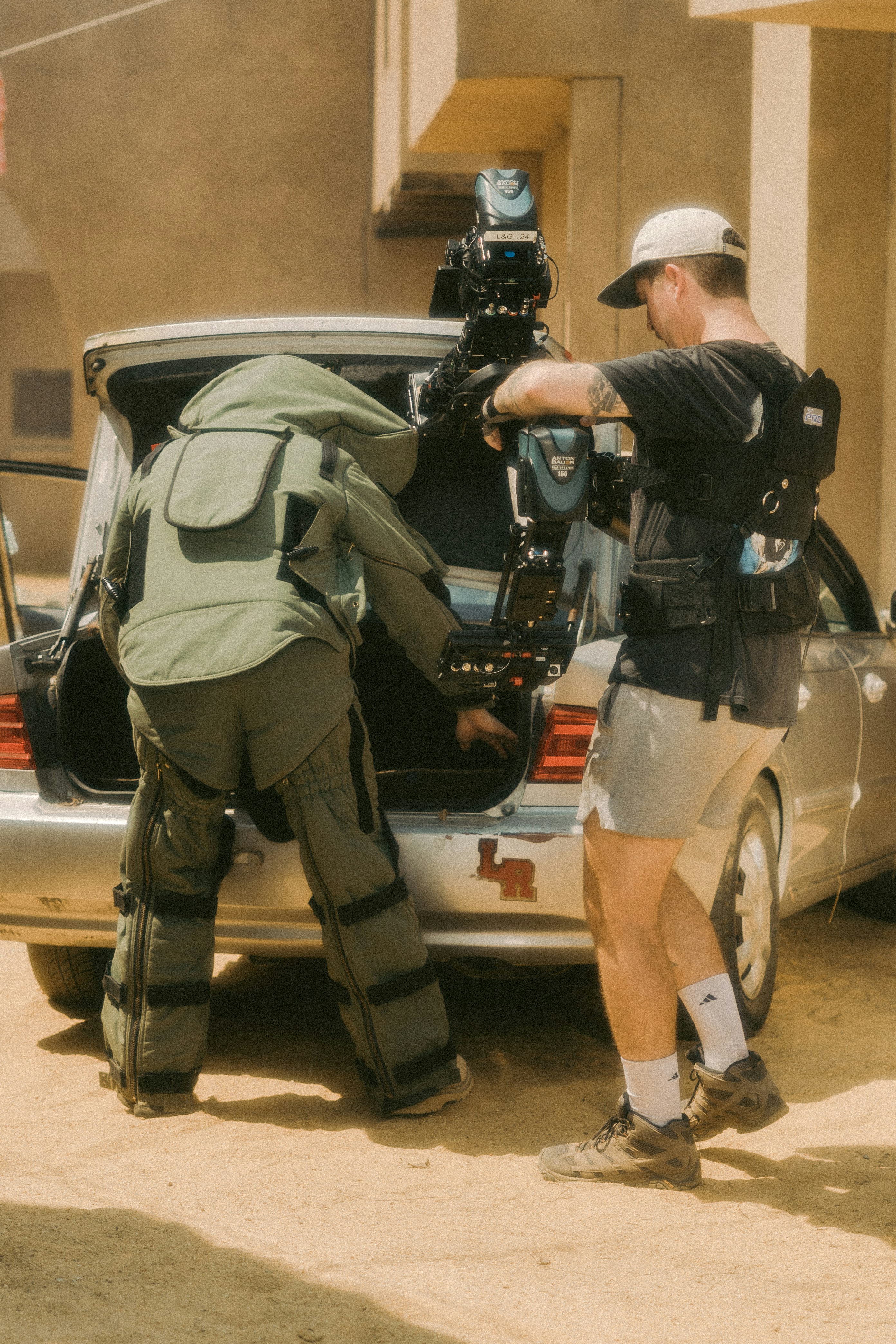 man in black and gray camouflage uniform and helmet standing beside black and white car